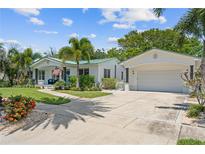 Charming home featuring a lovely landscaped yard, palm trees, and a welcoming front entrance and attached garage at 759 Lantana Ave, Clearwater Beach, FL 33767