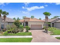 Beautiful single-story home featuring a brick driveway, lush landscaping, and a classic tile roof at 8605 Grand Alberato Rd, Tampa, FL 33647