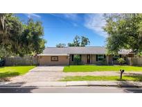 Cozy single story home featuring a red front door, green lawn, and mature trees at 915 S Miller Rd, Valrico, FL 33594