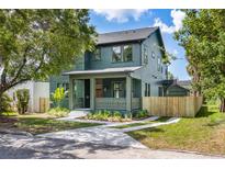 Charming two-story home with inviting front porch, landscaped yard, and new fence at 101 E Lambright St, Tampa, FL 33604