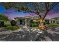 Charming home featuring a well-manicured lawn, mature landscaping, and inviting covered entrance illuminated at dusk at 1214 Haddington Cir # 1214, Sun City Center, FL 33573