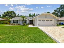 Charming single-story home with well-manicured lawn and a brick-paved driveway leading to an attached two-car garage at 15108 Winterwind Dr, Tampa, FL 33624