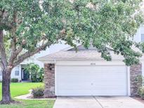 Attached one-car garage featuring stone accents and a white door, shaded by a mature tree at 19232 Stone Hedge Dr, Tampa, FL 33647