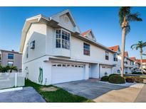 Bright daytime view of a charming two-story townhome featuring an attached one-car garage and well-maintained landscaping at 19717 Gulf Blvd # V5, Indian Shores, FL 33785