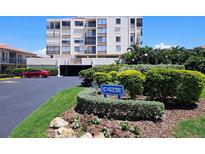 Exterior shot of a white condo building with balconies, lush landscaping, and a community sign at 6218 Palma Del Mar S Blvd # 503, St Petersburg, FL 33715