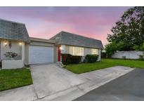 Charming home featuring a well-manicured lawn, red door, and attached garage at dusk at 8447 Orleans N, Pinellas Park, FL 33781