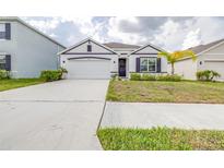 Charming single-story home showcasing a well-manicured lawn, neutral paint scheme, and attached two-car garage at 9098 Forge Breeze Loop, Wesley Chapel, FL 33545