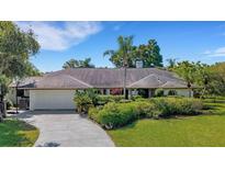 Charming single-story home featuring a lush landscaped front yard and a spacious two-car garage at 1000 Chatham Ct, Safety Harbor, FL 34695