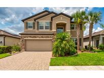 Beautiful two-story home with a brick-accented facade, attached two-car garage, and professionally landscaped front yard at 11035 Sage Canyon Dr, Riverview, FL 33578