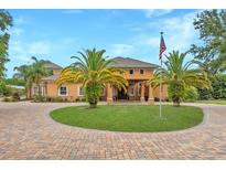 Beautiful custom home featuring lush landscaping, circular driveway and grand entrance with American flag at 11430 Trotting Down Dr, Odessa, FL 33556
