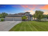 Beautiful single-story home featuring a well-manicured lawn, three-car garage and elegant architectural details at 12637 Tyler Run Ave, Odessa, FL 33556