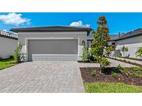 Exterior shot of a two-car garage with a paver driveway and manicured landscaping and house number 14317 at 14317 Eagle Branch Dr, Nokomis, FL 34275