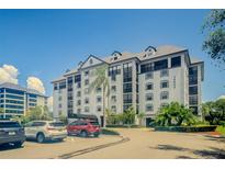 A large building with multiple cars parked out front surrounded by landscaping and clear blue skies at 14820 Rue De Bayonne # 301, Clearwater, FL 33762