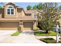 Charming townhome featuring a tan stucco exterior, two-car garage, and well-maintained landscaping at 18809 Duquesne Dr, Tampa, FL 33647