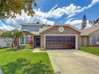 Charming single-Gathering home with a brown garage door, landscaped yard, and a stone facade at 2254 Springrain Dr, Clearwater, FL 33763
