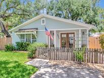 Charming single-story home with a picket fence, lush greenery, and an American flag waving at 2822 W Bay Ave, Tampa, FL 33611