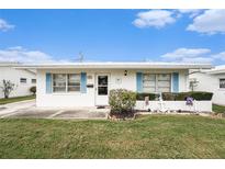 Charming home featuring bright blue shutters, a white exterior, a manicured lawn, and coastal-themed decor at 4325 93Rd N Ter, Pinellas Park, FL 33782