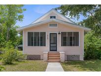 Charming, light pink home featuring a screened-in porch with brick-lined stairs and a well-maintained yard at 459 Bell Ave, Brooksville, FL 34601