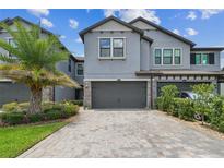 Stylish two-story townhome with a two-car garage, beautiful landscaping, and brick paver driveway at 4653 Ancona Way, Wesley Chapel, FL 33543
