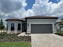 Charming single-story home featuring a tile roof, paver driveway, and gray exterior paint at 6162 Winding Pine Dr, Nokomis, FL 34275