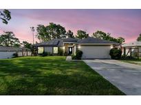 Charming home featuring a well-manicured lawn, double door entry, and a two-car garage at 13441 Barlington St, Spring Hill, FL 34609
