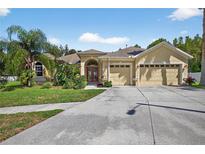 Inviting single-story home with lush landscaping, palm tree and a three-car garage at 1835 Fircrest Ct, Wesley Chapel, FL 33543
