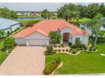 Beautiful home featuring a well-manicured lawn, a paver driveway, and a three-car garage, complemented by a lovely lake view at 2221 Platinum Dr, Sun City Center, FL 33573