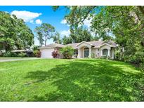 Charming single-story home featuring a lush green lawn, beautiful landscaping, and a two-car garage at 2454 Shadecrest Rd, Land O Lakes, FL 34639