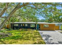 Charming single-story home with a well-manicured lawn, vibrant landscaping and brick driveway at 412 Mira Vista Dr, Dunedin, FL 34698