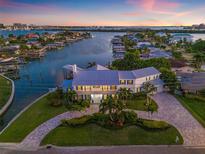 Stunning waterfront home featuring lush landscaping, private boat dock, and bay access on a gorgeous sunset evening at 511 Windward Psge, Clearwater Beach, FL 33767
