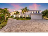 Elegant two-story home with a circular driveway, lush landscaping, and a spacious two-car garage at 511 Windward Psge, Clearwater Beach, FL 33767