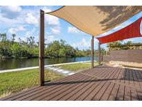 Waterfront property featuring a wooden deck, canvas awnings, and beautifully landscaped surroundings at 6814 68Th E Ave, Bradenton, FL 34203