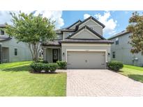 Charming two-story home features a well-manicured lawn, brick paved driveway and an attached two-car garage at 12382 Tibbetts St, Odessa, FL 33556