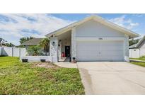 Charming single-story home showcasing a well-maintained front yard and a two-car garage at 1304 Cedar Ct, Tarpon Springs, FL 34689
