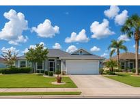 Charming single-story home featuring a well-manicured lawn, beautiful landscaping, and an attached two-car garage at 1607 Alexander Crossing Way, Sun City Center, FL 33573