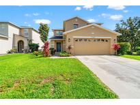 Two-story home with a manicured lawn, long driveway, and a beige two-car garage at 17509 Queensland St, Land O Lakes, FL 34638