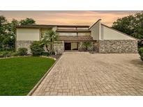 Contemporary home with stone accents, professional landscaping, and a brick driveway at 2103 N Golfview Dr, Plant City, FL 33566