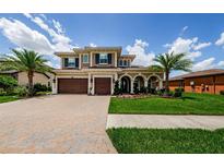 Stunning two-story home featuring a three-car garage, arched entryway, and professionally landscaped yard at 29038 Picana Ln, Wesley Chapel, FL 33543