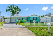 Charming turquoise single-story home featuring a white picket fence and attached carport at 5107 Pine St, Seffner, FL 33584