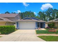 Charming single-story home with a well-maintained lawn, lush landscaping, and two car garage at 7010 Kendall Heath Way, Land O Lakes, FL 34637