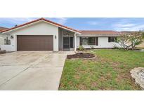 Charming single-story home featuring a brown garage door, red roof tiles and a well manicured front lawn at 734 Flamingo Dr, Apollo Beach, FL 33572