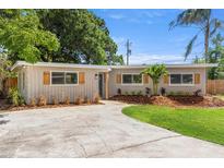 Charming single-story home featuring a well-manicured lawn, gray paint, dark shutters, and a concrete driveway at 8485 Pelican Ln, Seminole, FL 33777