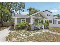 Charming gray home featuring a cozy front porch and beautiful landscaping at 120 W Sligh Ave, Tampa, FL 33604