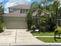 Charming home featuring a two-car garage and a well-manicured lawn with lush tropical landscaping at 1247 Gentilly Ln, Wesley Chapel, FL 33544