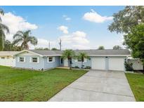 Charming single-story home with blue exterior, lush lawn, and a two-car garage at 2165 Campus Dr, Clearwater, FL 33764