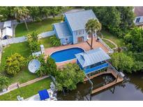 Stunning aerial view of a waterfront home featuring a private pool, boat dock, and lush landscaping at 428 Klosterman W Rd, Palm Harbor, FL 34683