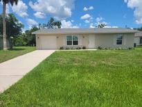 Charming single-story home with a well-manicured lawn, a neutral color palette, and an attached garage at 474 Hinton St, Port Charlotte, FL 33954