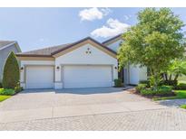 Charming home featuring a three-car garage and brick-paved driveway, complemented by well-maintained landscaping at 6331 Voyagers Pl, Apollo Beach, FL 33572