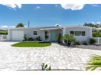 Charming single-story home with a well-manicured lawn, turquoise door, and patterned brick driveway at 6511 10Th N St, St Petersburg, FL 33702