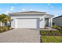 Charming one-story home with a pristine white exterior, brick driveway, and well manicured landscaping at 10463 Abaco Falls Dr, Englewood, FL 34223